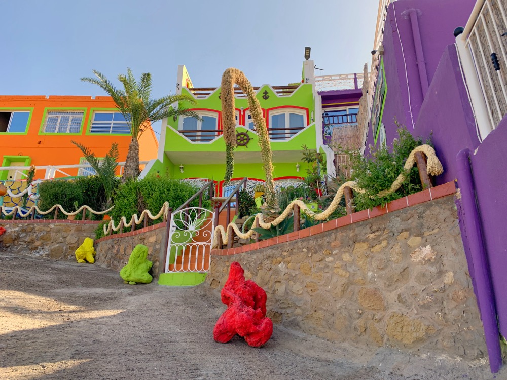 Vibrant colorful houses of Aghroud Rainbow Village with decorative stone walls and artistic sculptures along the beach Morocco
